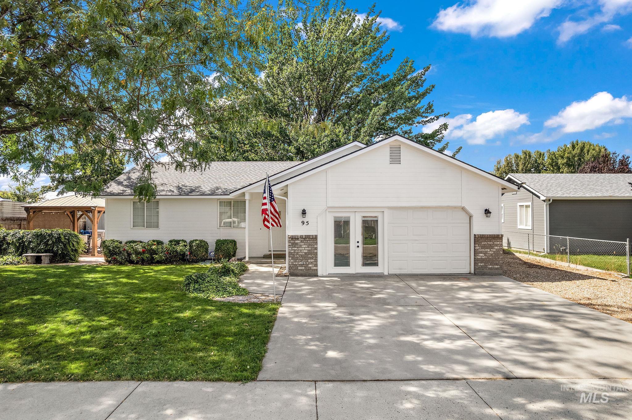 Single story home featuring brick siding, concrete driveway, and french doors
