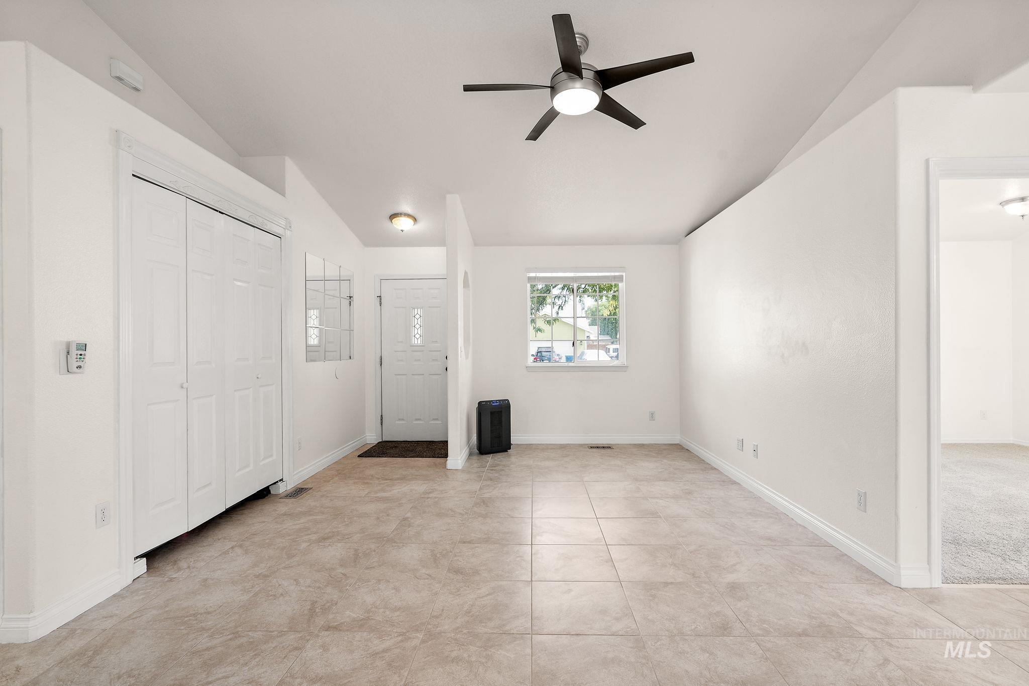 Unfurnished bedroom featuring ceiling fan, light tile patterned floors, and vaulted ceiling