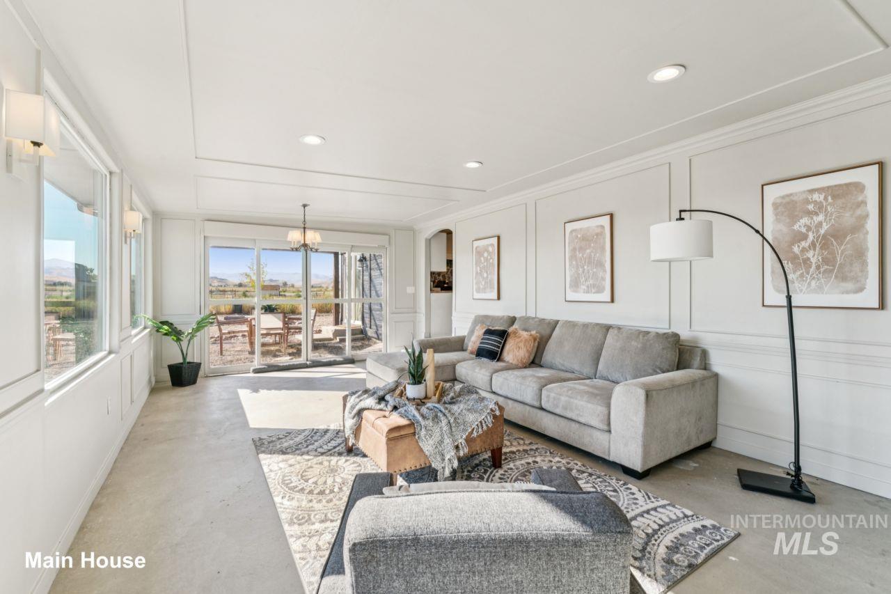 Living room featuring a decorative wall, concrete flooring, recessed lighting, a chandelier, and crown molding