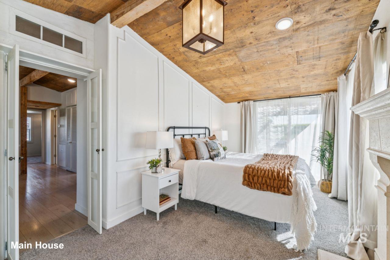 Bedroom with a decorative wall, multiple windows, carpet, and wooden ceiling