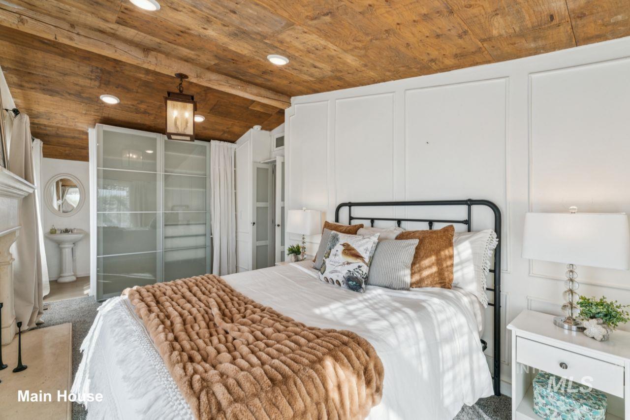 Bedroom featuring vaulted ceiling, a decorative wall, wood ceiling, and recessed lighting