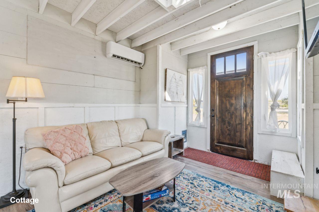 Living room featuring beam ceiling, wood finished floors, and a wall unit AC