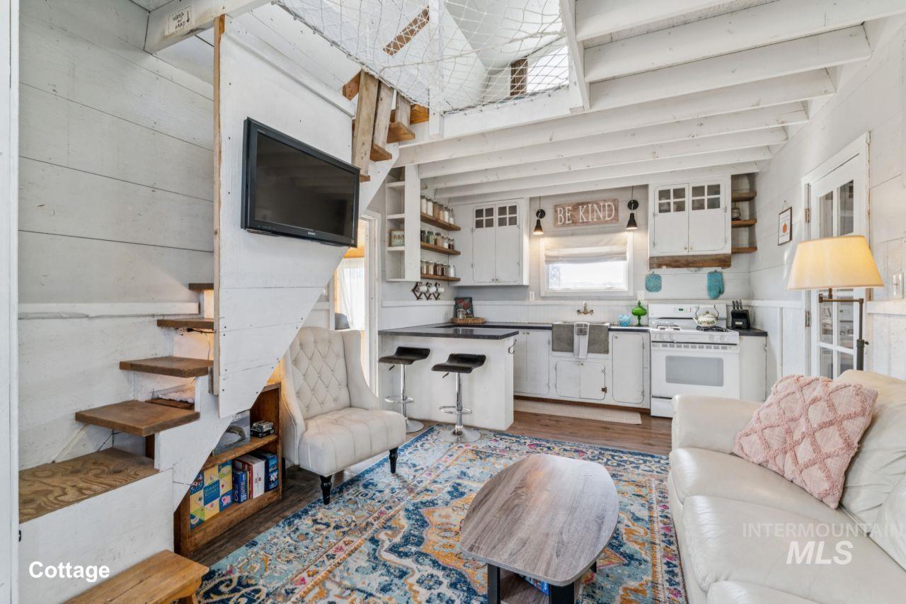 Living area with stairs, wood finished floors, beam ceiling, and wooden walls