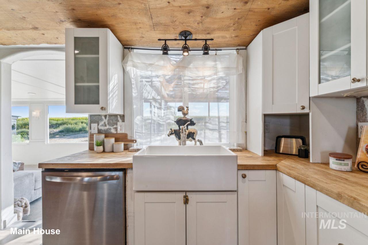 Kitchen featuring glass insert cabinets, dishwasher, healthy amount of natural light, and white cabinets