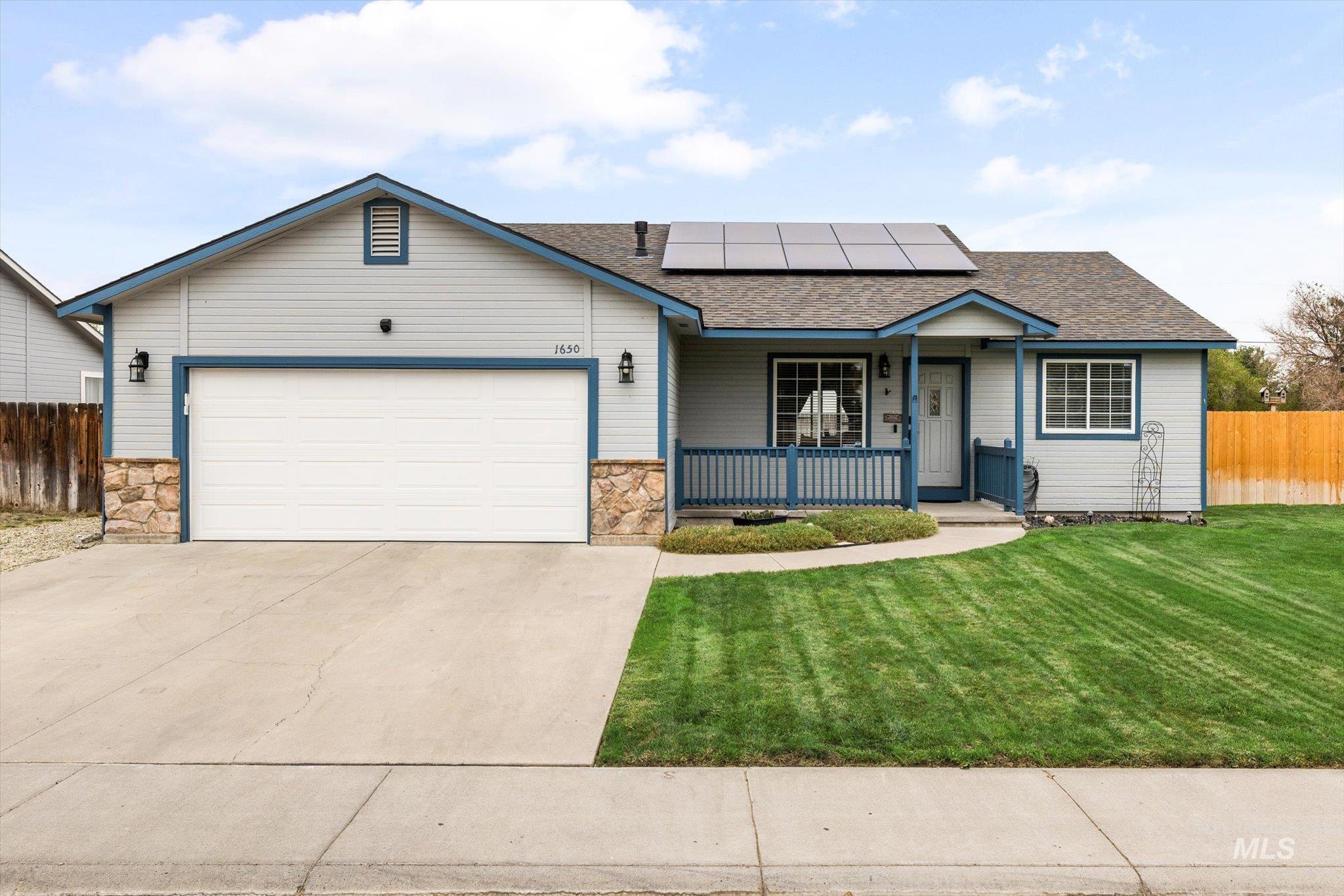 Ranch-style house with a porch, stone siding, solar panels, and concrete driveway