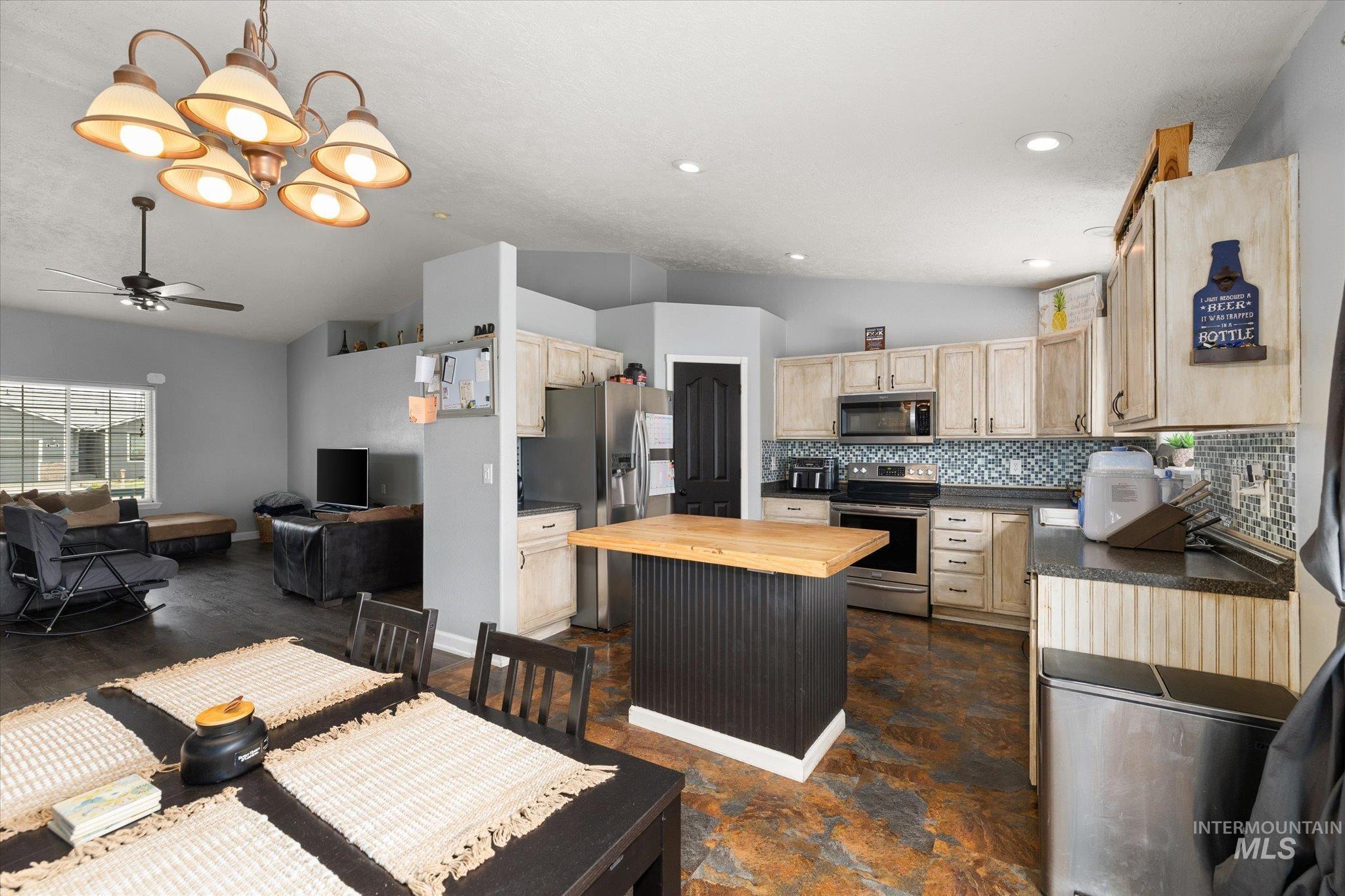 Kitchen featuring butcher block counters, lofted ceiling, light brown cabinetry, stainless steel appliances, and tasteful backsplash