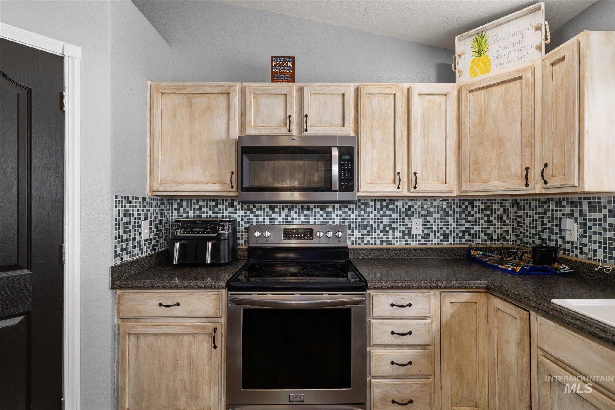 Kitchen featuring light brown cabinets, stainless steel appliances, and backsplash