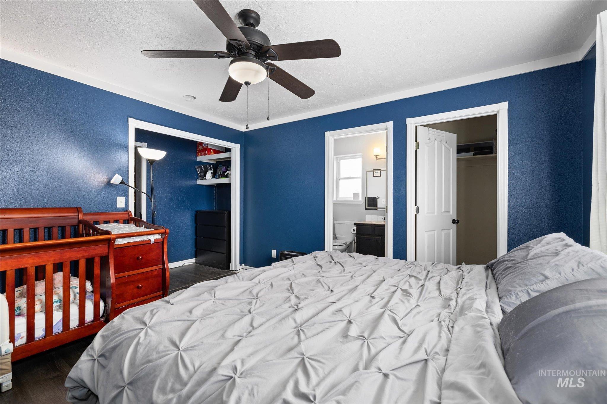 Bedroom featuring a textured wall, dark wood finished floors, a closet, a ceiling fan, and a textured ceiling