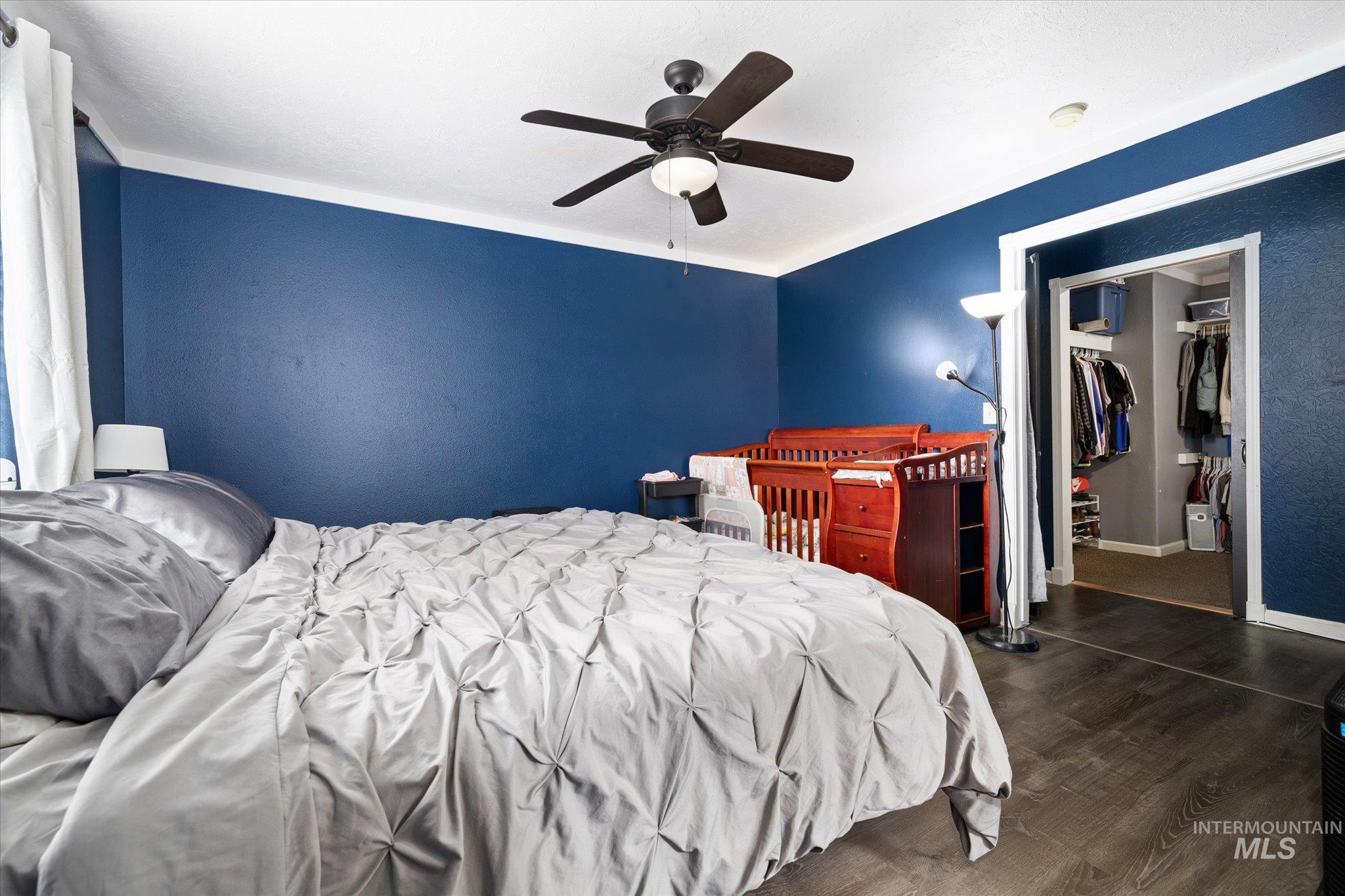 Bedroom featuring dark wood-style floors, ceiling fan, and a walk in closet
