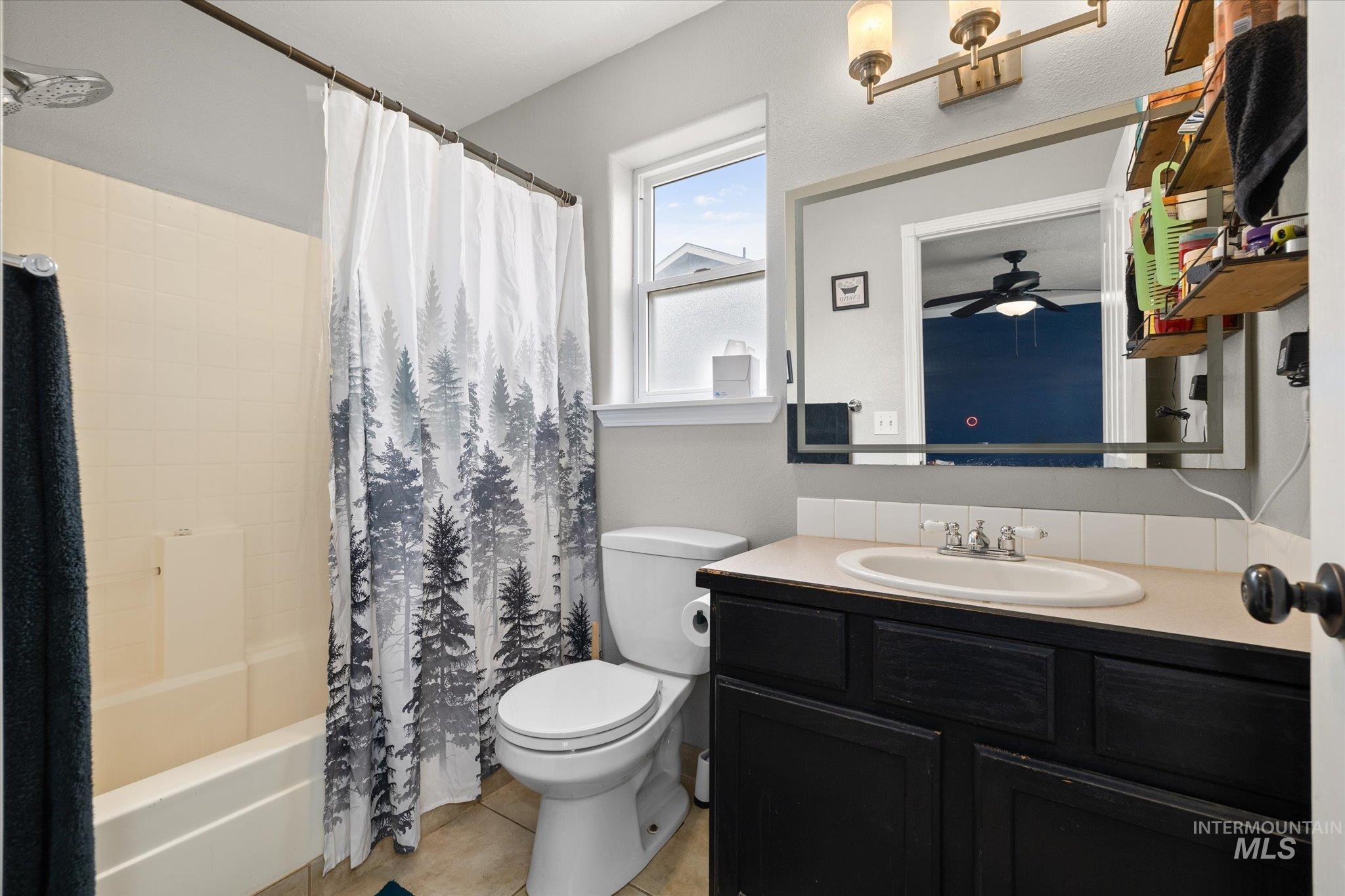 Bathroom featuring shower / tub combo, vanity, light tile patterned flooring, and ceiling fan