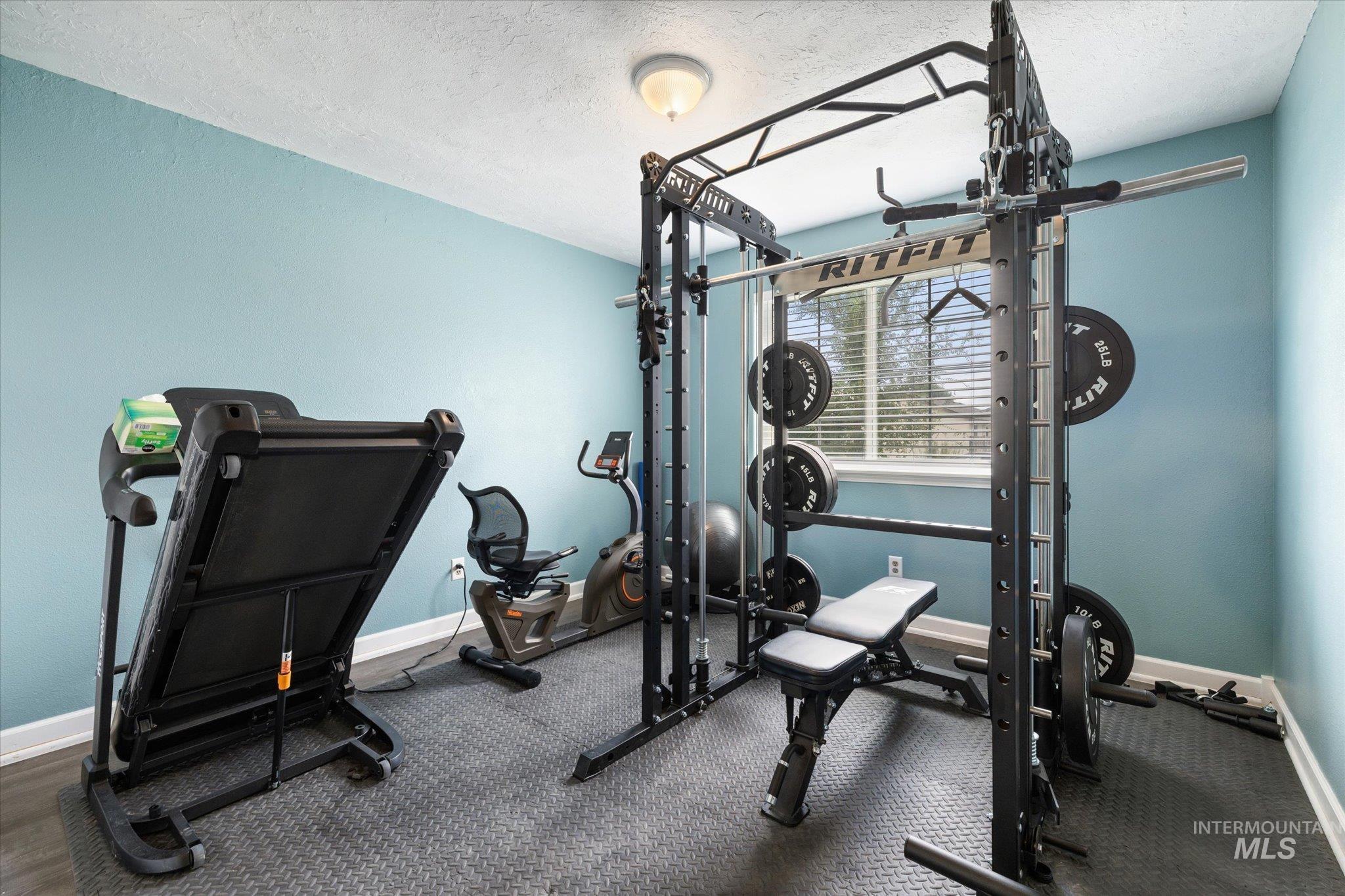 Workout room featuring baseboards and a textured ceiling