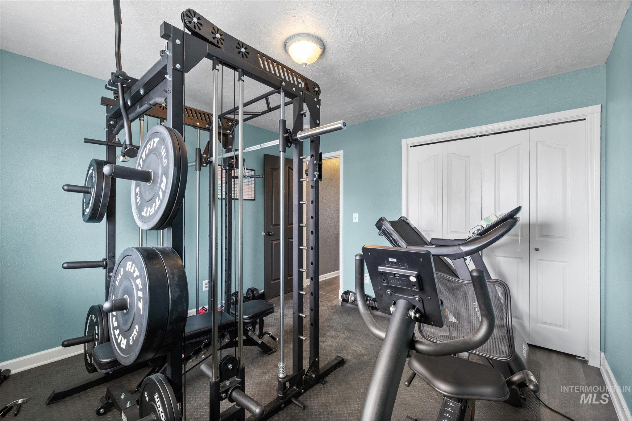 Workout room featuring baseboards and a textured ceiling