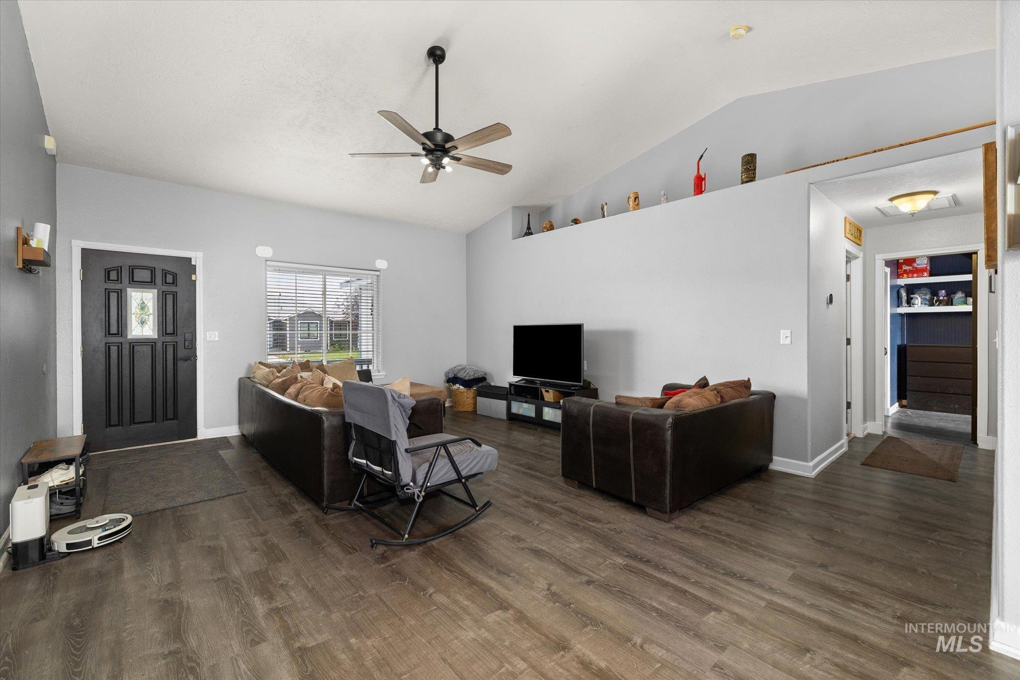 Living area featuring ceiling fan, dark wood finished floors, and lofted ceiling