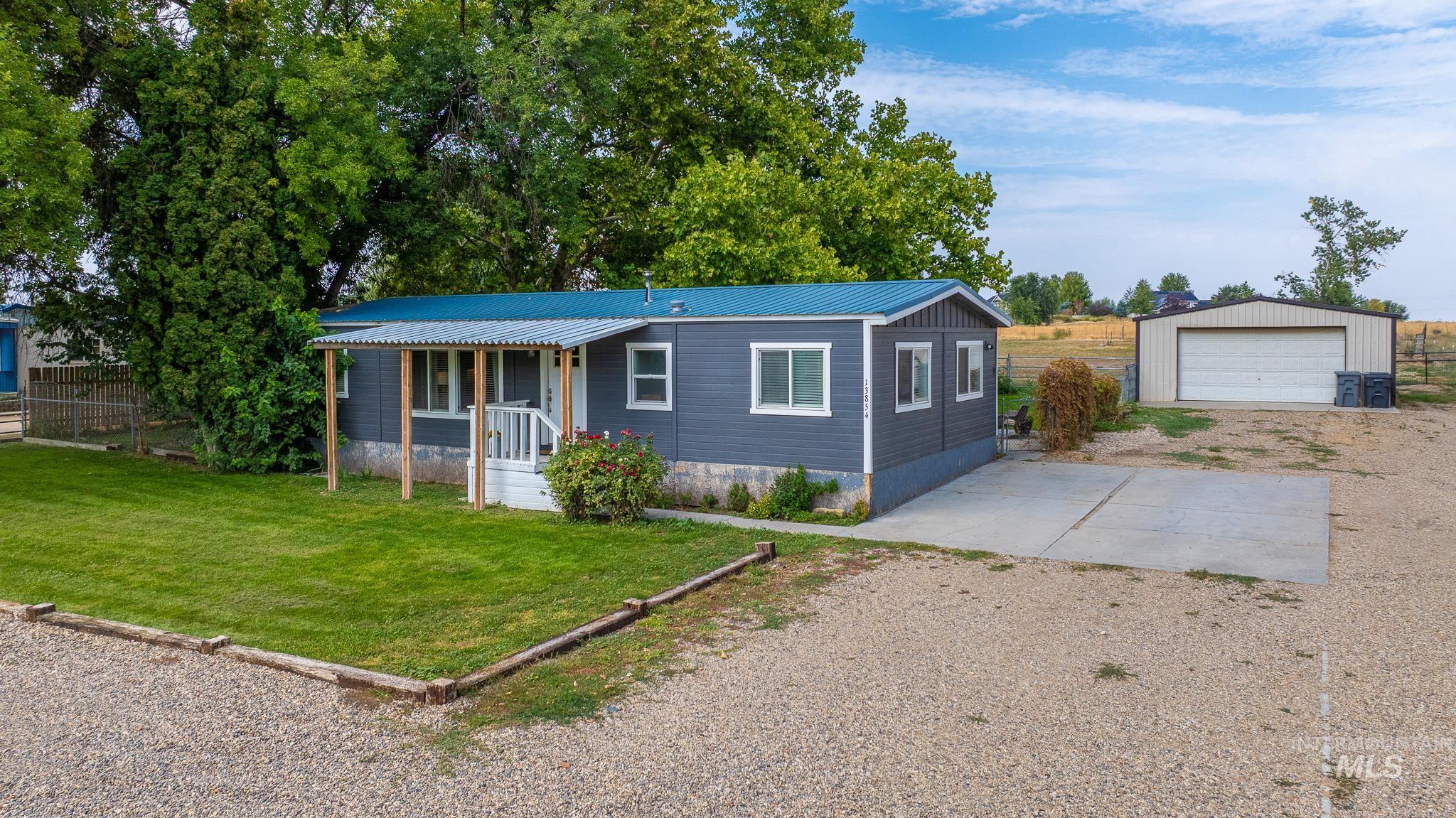 View of front of property featuring driveway, a metal roof, an outdoor structure, a garage, and a front yard