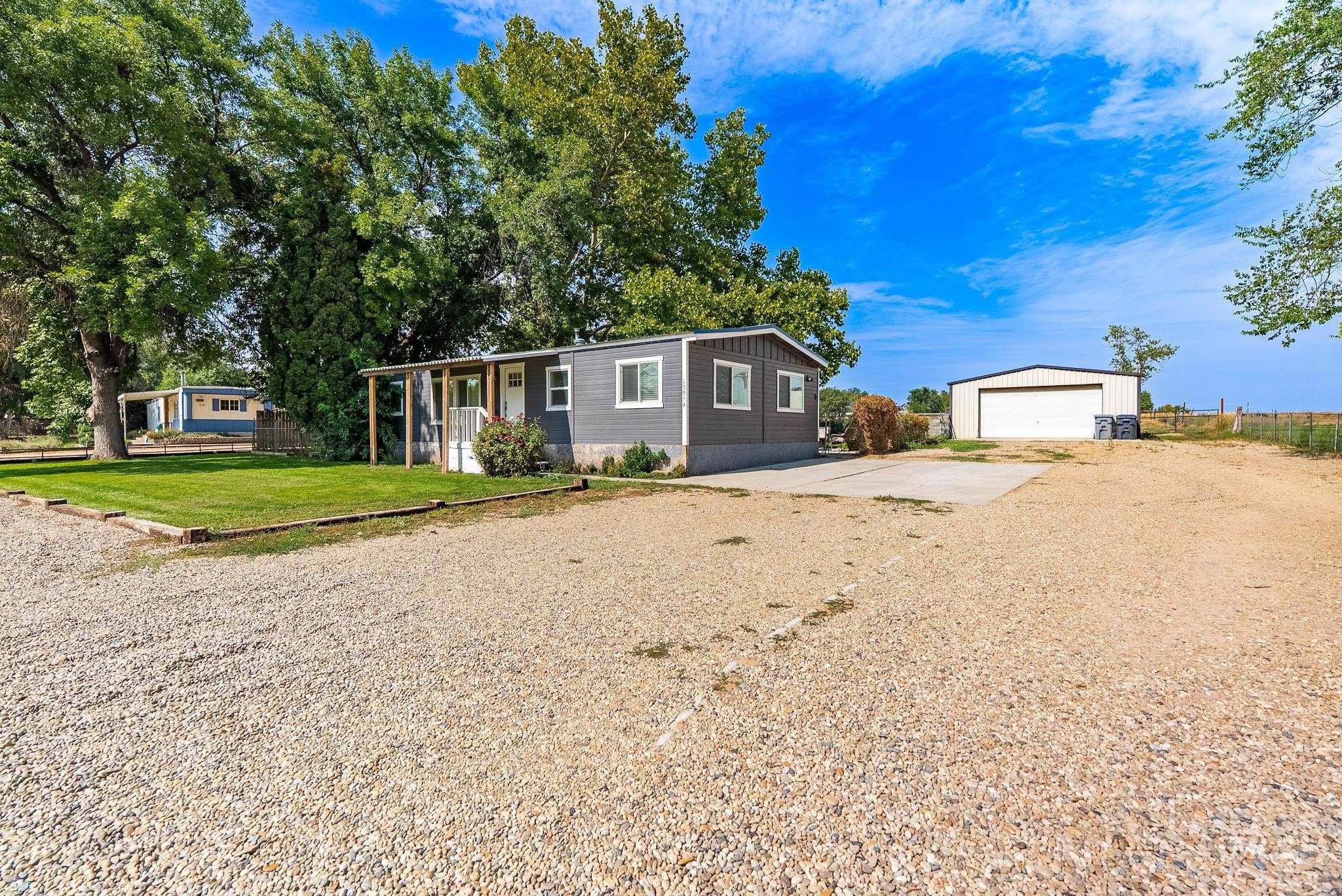 Manufactured / mobile home with a garage, an outdoor structure, a front yard, driveway, and a porch