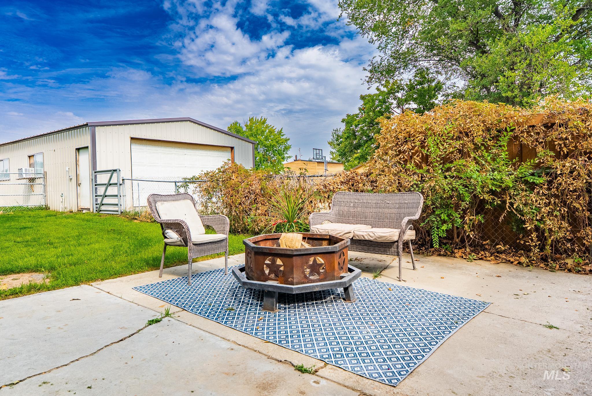 View of patio featuring a fire pit, an outdoor structure, and a detached garage