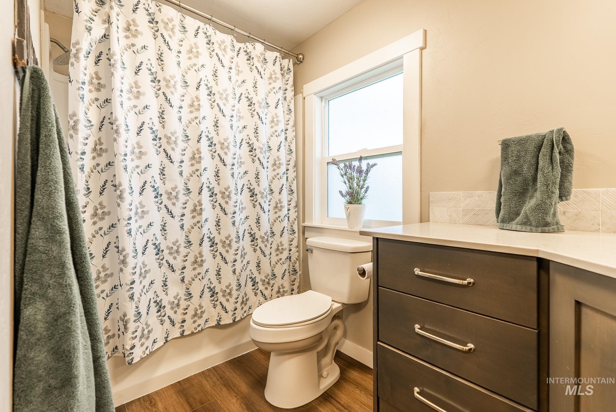 Full bathroom with wood finished floors, vanity, and shower / bath combo with shower curtain
