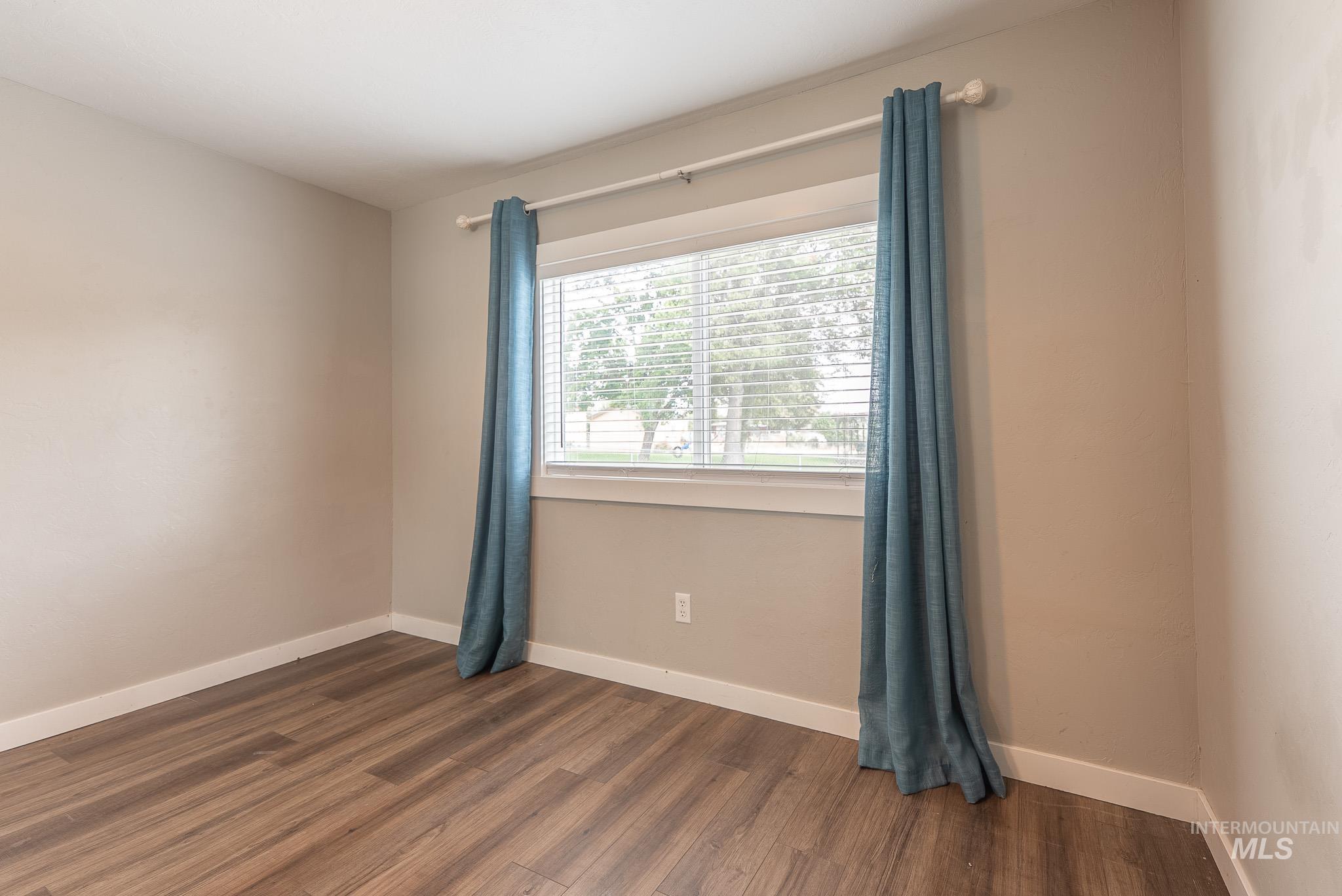 Spare room featuring baseboards and dark wood-style flooring