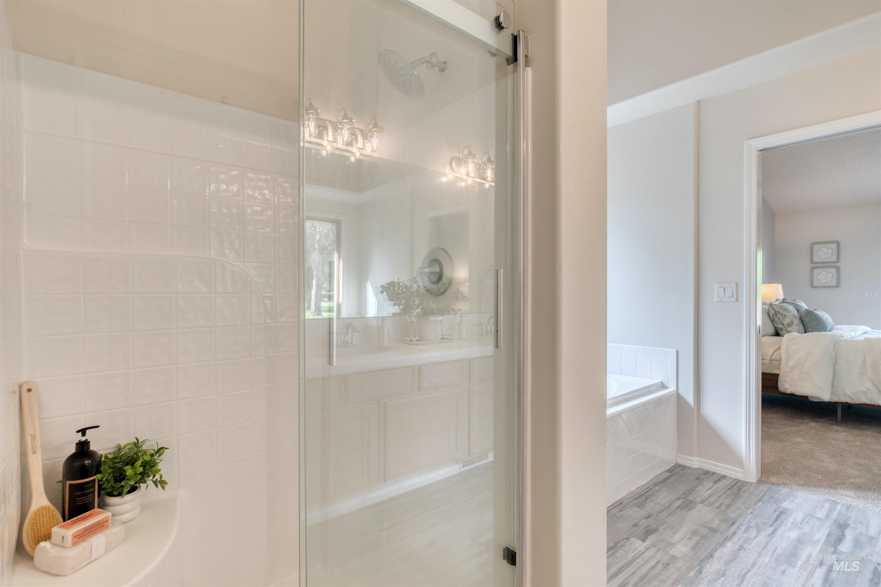 Bathroom featuring ensuite bathroom, light wood finished floors, a bath, and a shower with shower door
