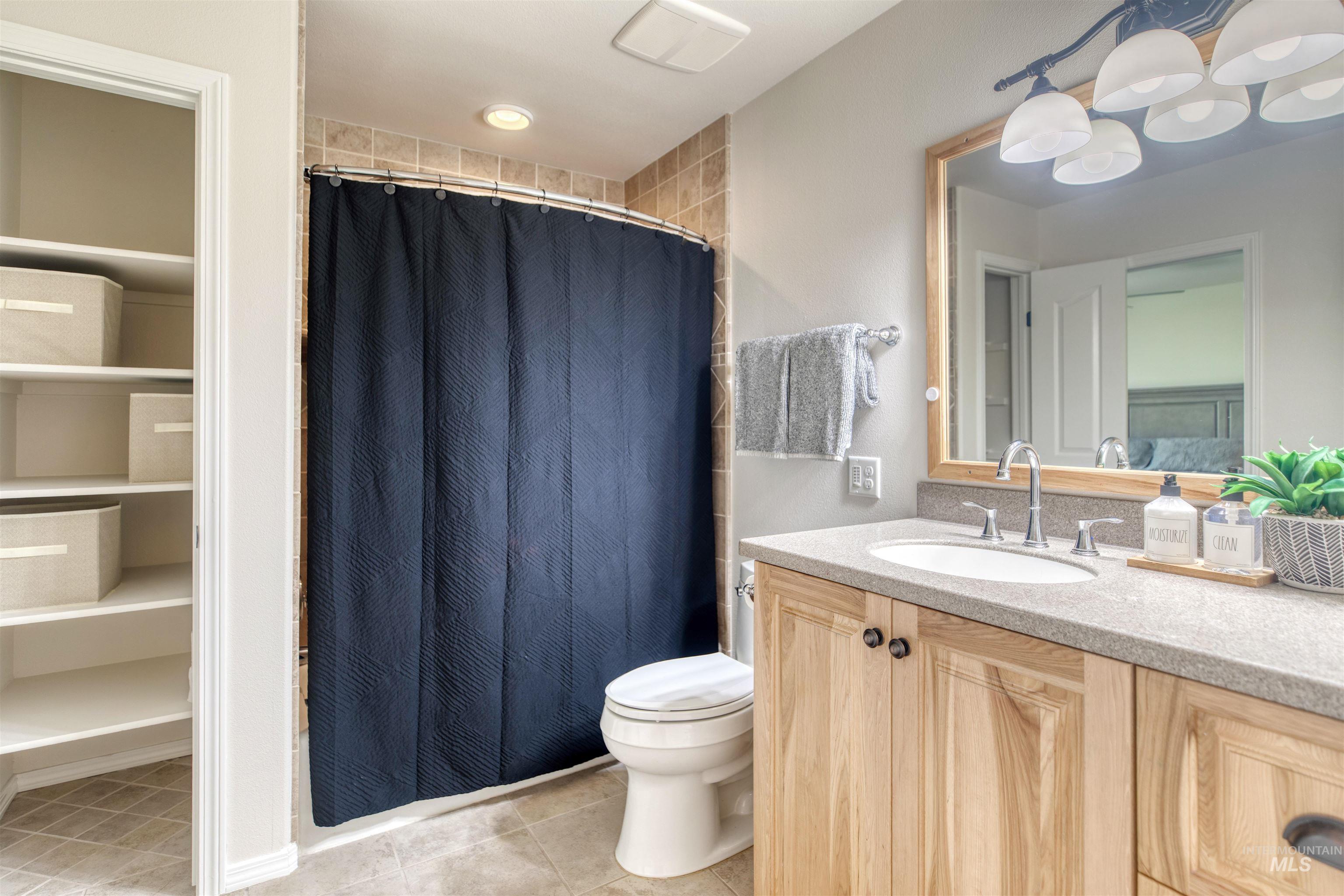 Bathroom with a shower with curtain, vanity, light tile patterned floors, and a closet