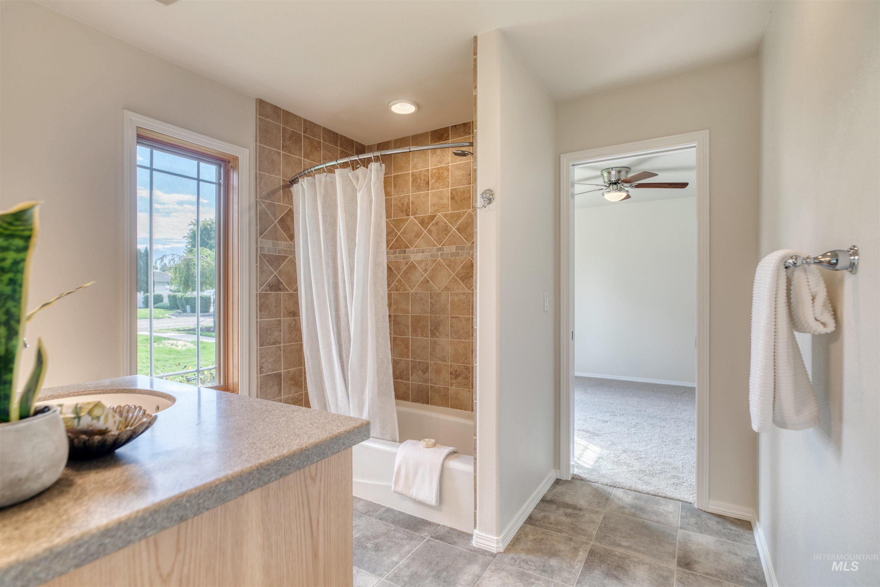 Bathroom featuring shower / bath combination with curtain, vanity, ceiling fan, and light tile patterned floors