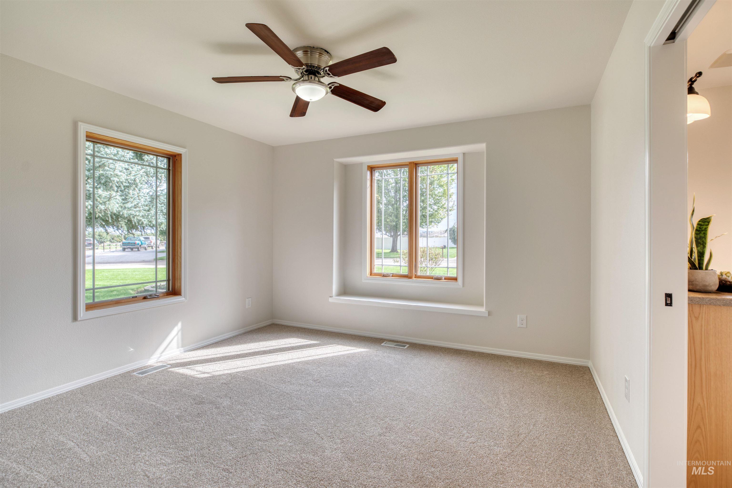 Carpeted spare room featuring baseboards and ceiling fan