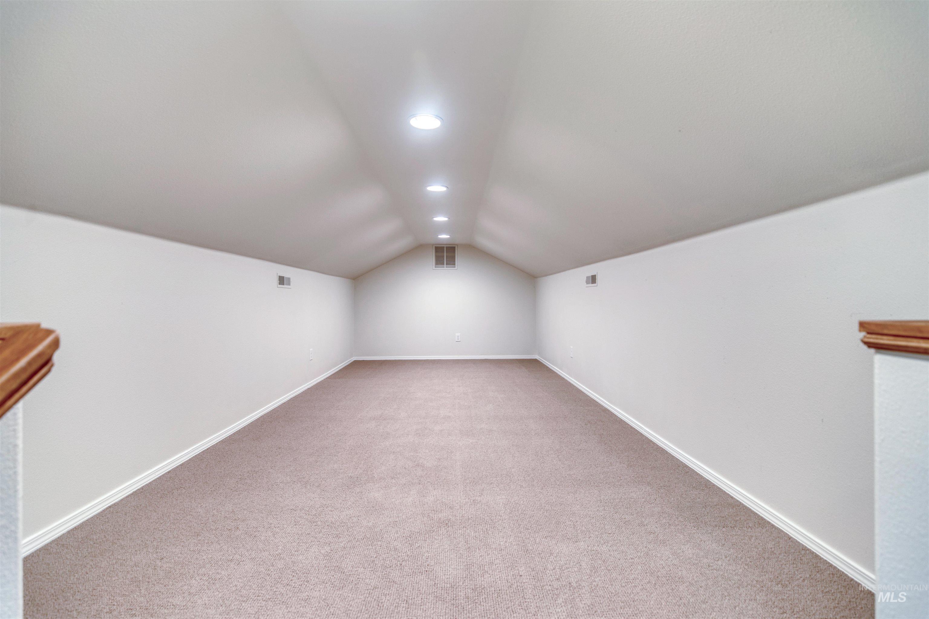 Additional living space with vaulted ceiling, light carpet, and recessed lighting