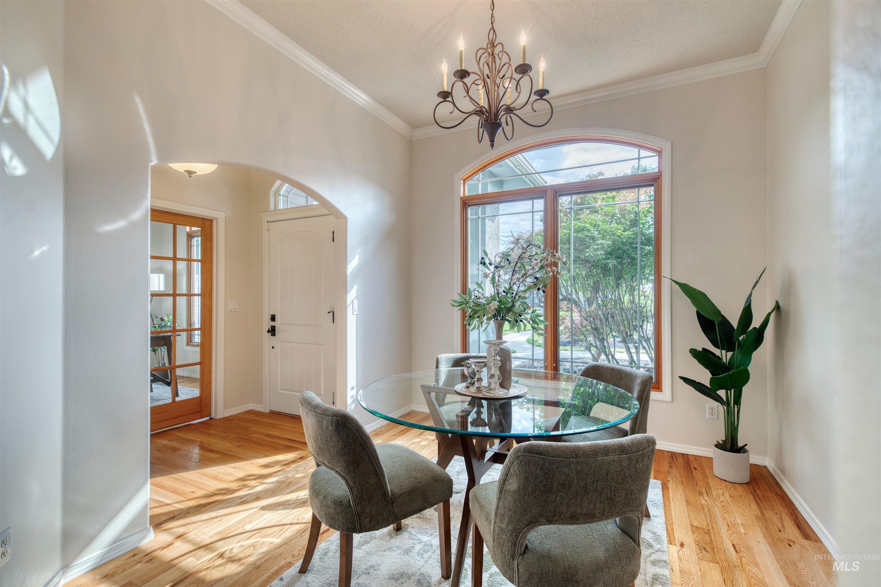 Dining area featuring light wood-style flooring, ornamental molding, and a chandelier