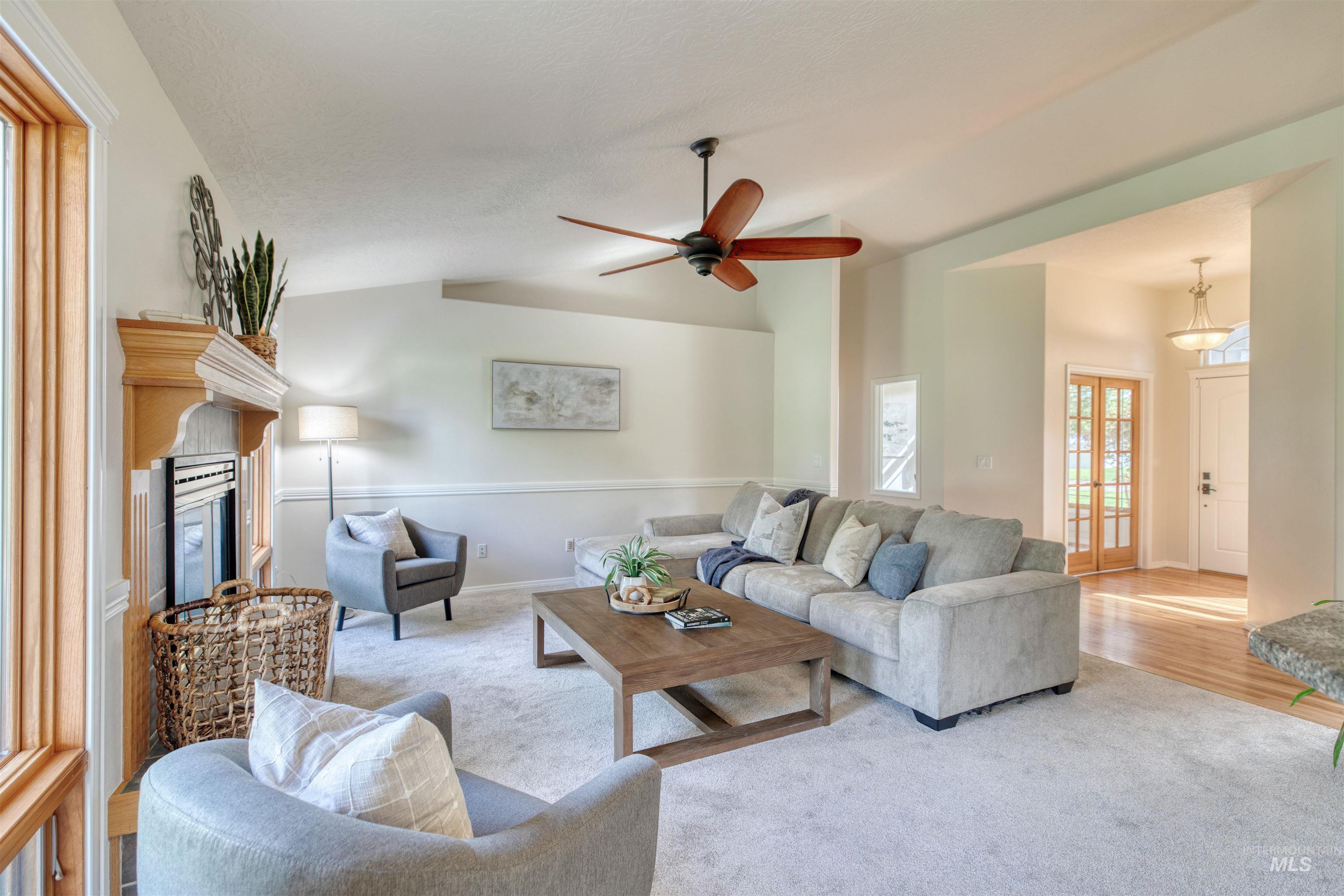 Living room with carpet flooring, lofted ceiling, a glass covered fireplace, and ceiling fan