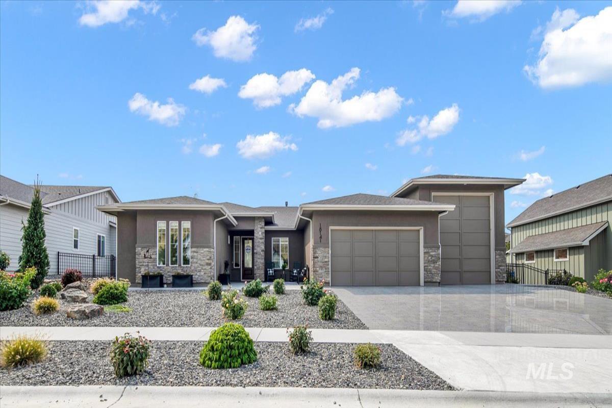 Prairie-style house with stone siding, a garage, concrete driveway, and stucco siding