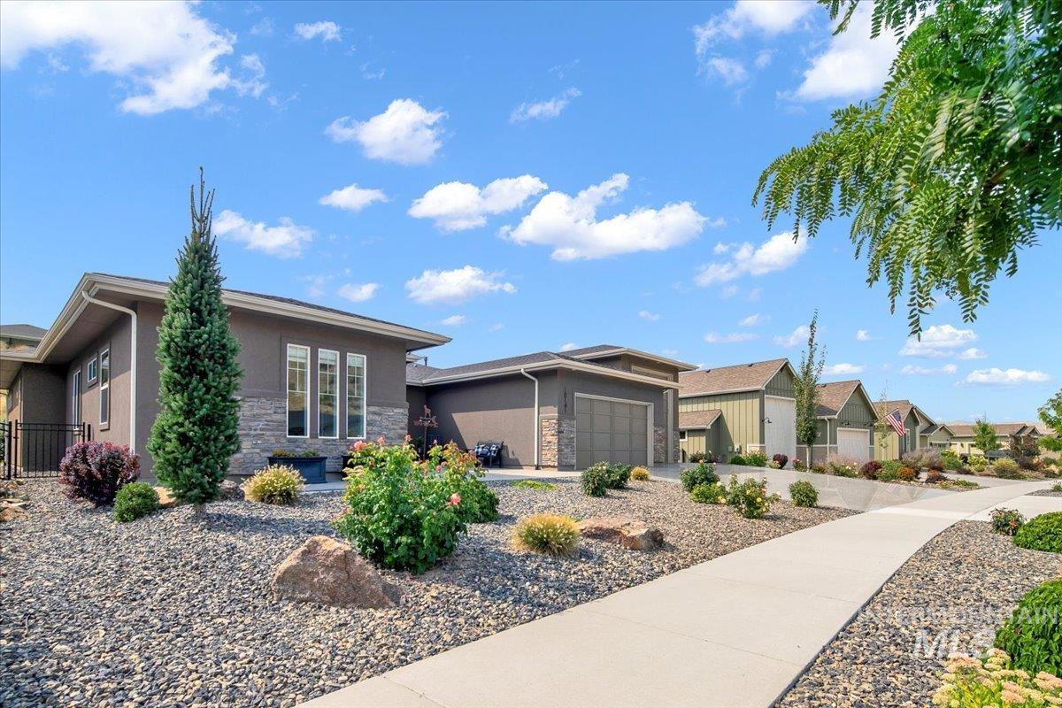 View of front of property with stone siding, stucco siding, a garage, and a residential view