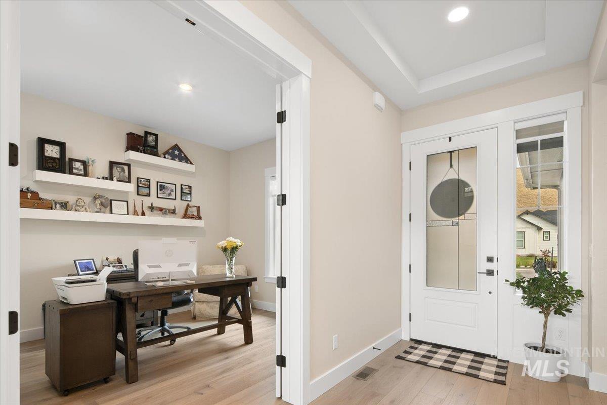Foyer entrance with light wood-type flooring, recessed lighting, and a tray ceiling