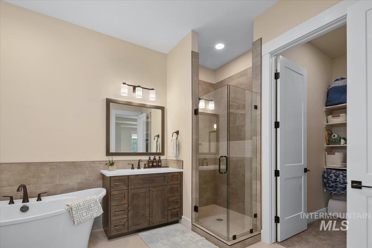 Bathroom with a freestanding bath, vanity, a stall shower, tile walls, and recessed lighting
