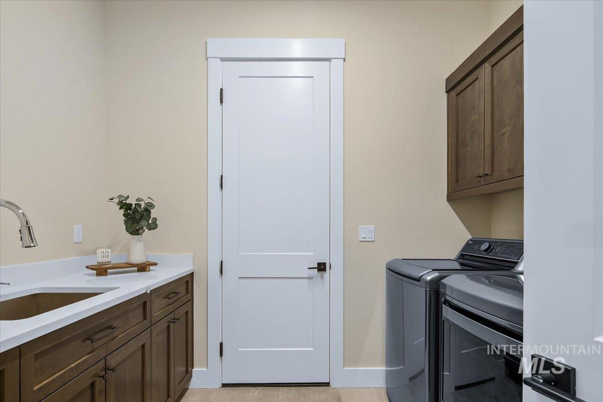 Laundry area featuring cabinet space, washer and clothes dryer, and light tile patterned flooring
