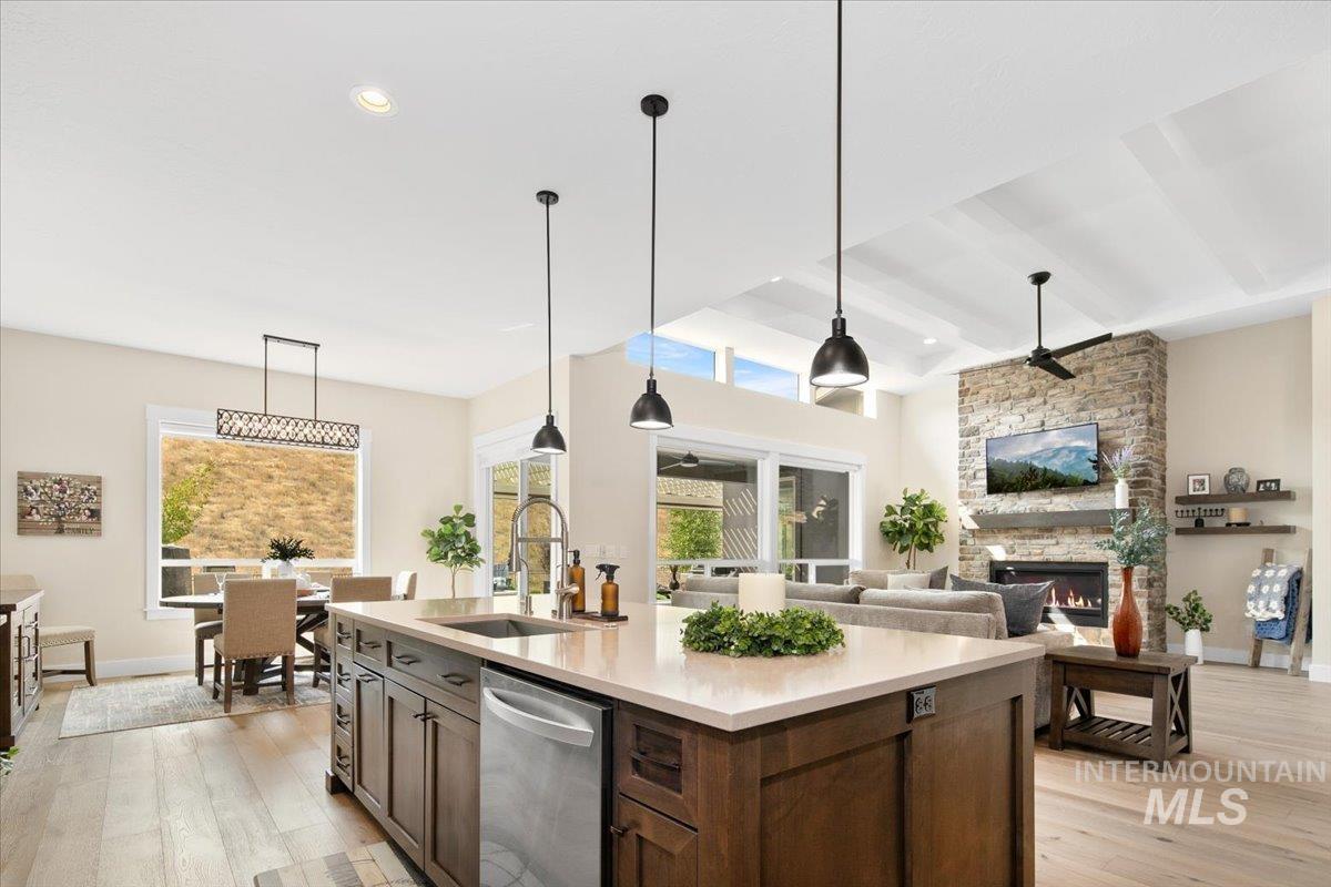 Kitchen with pendant lighting, light wood-style flooring, stainless steel dishwasher, a fireplace, and recessed lighting
