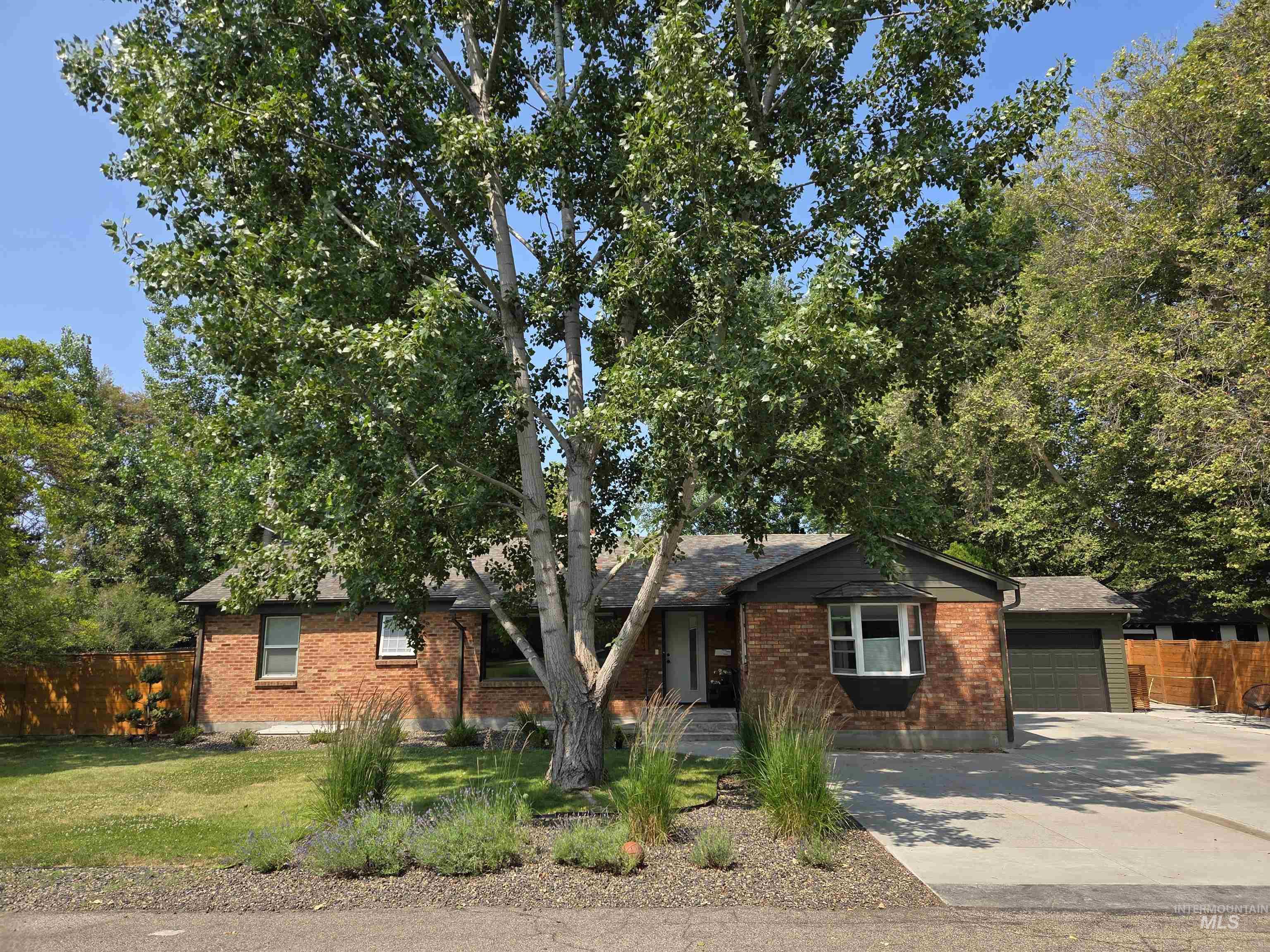 View of front of property with an attached garage, concrete driveway, and brick siding