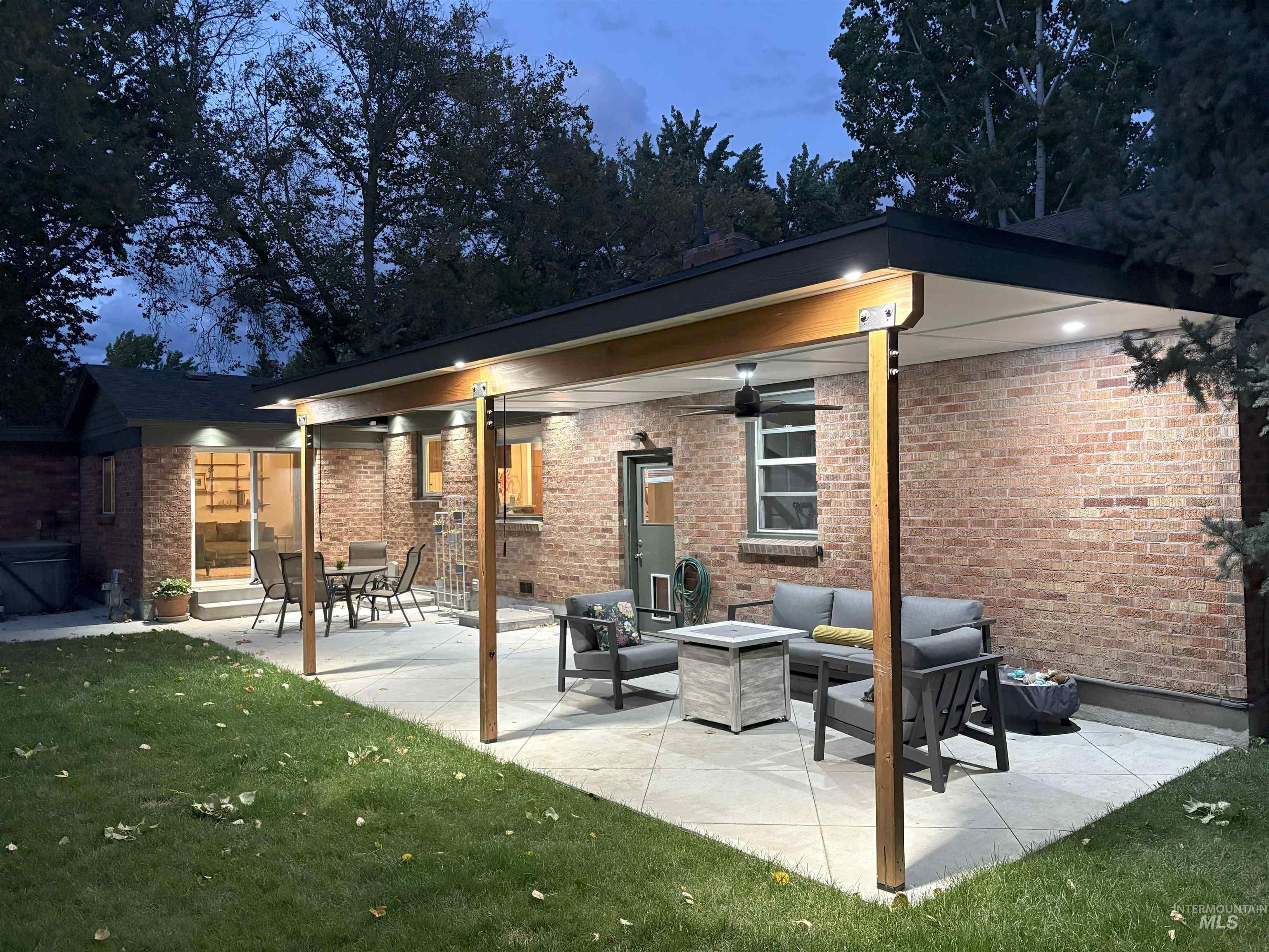 Back of property with an outdoor hangout area, a patio area, brick siding, a lawn, and a ceiling fan