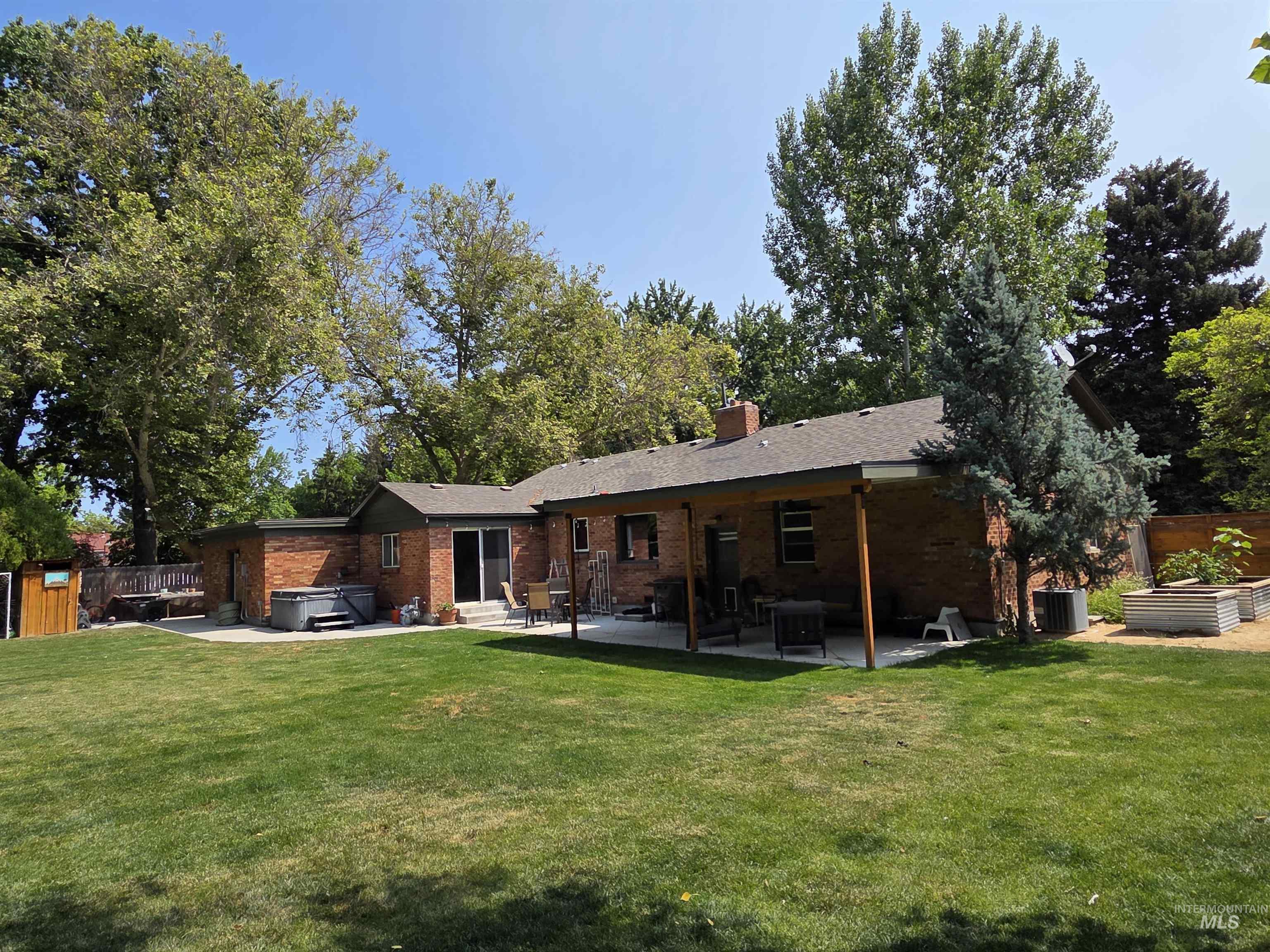 Back of property featuring a hot tub, a patio area, brick siding, and a chimney
