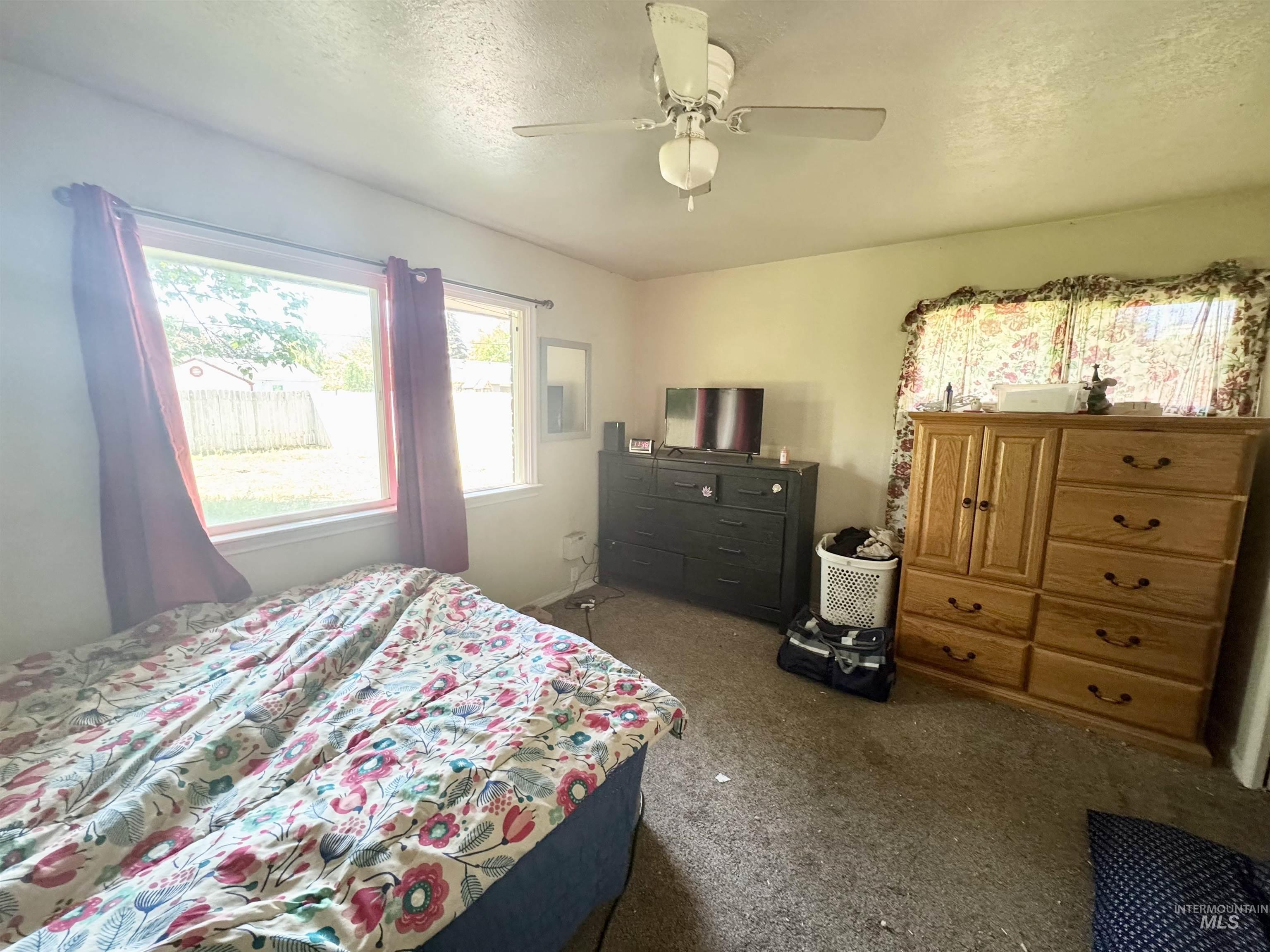 Carpeted bedroom featuring a textured ceiling and ceiling fan
