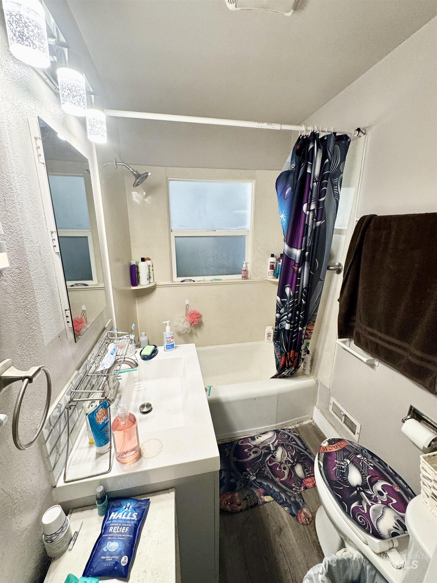 Full bath featuring shower / bathtub combination with curtain, wood finished floors, and vanity