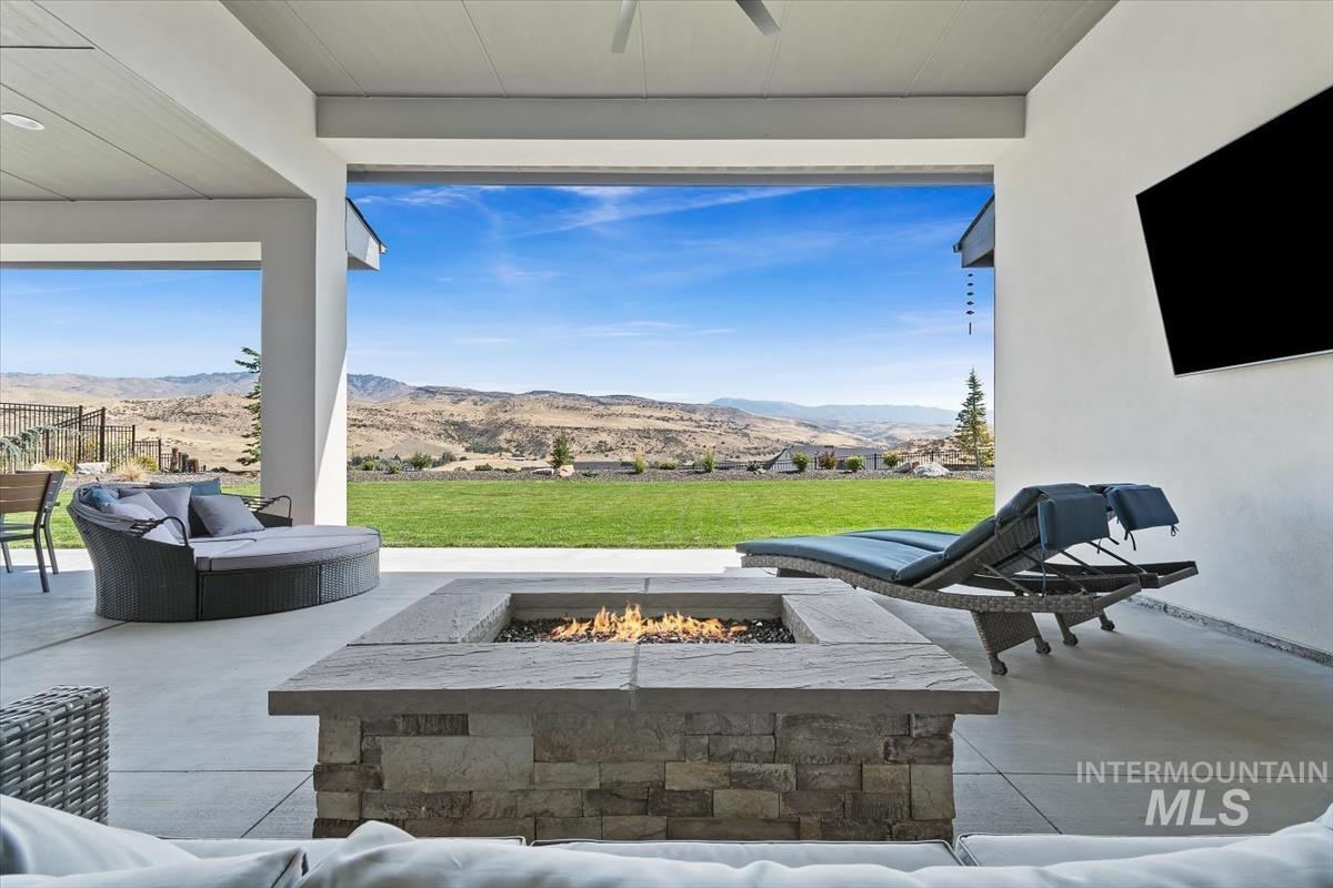 View of patio with ceiling fan and an outdoor living space with a fire pit