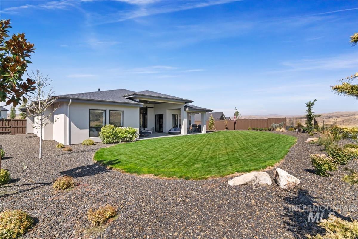 Rear view of house with a fenced backyard, stucco siding, a patio area, and roof with shingles
