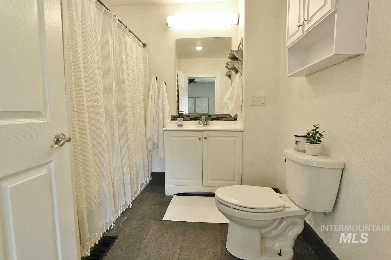 Full bath featuring vanity, dark tile patterned floors, and a shower with curtain