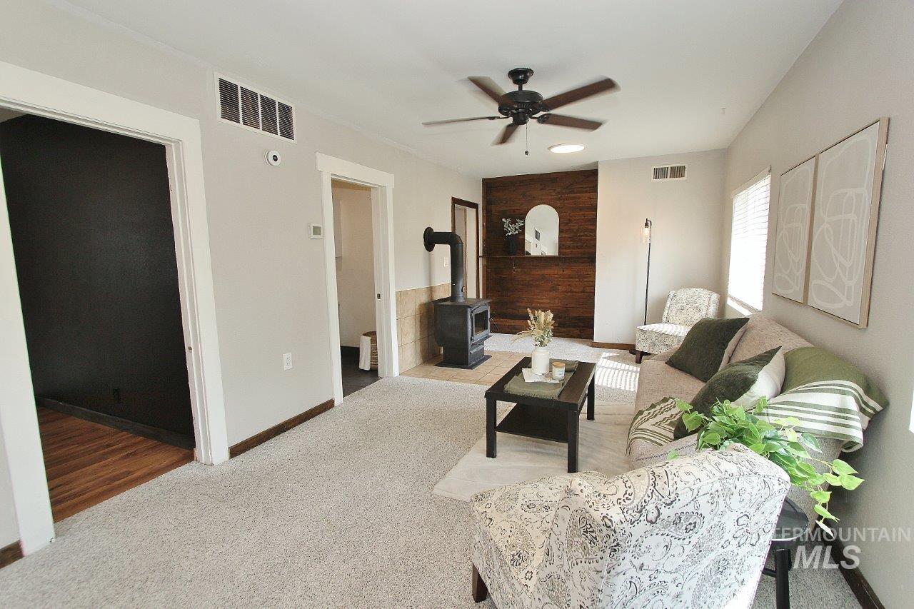 Carpeted living room featuring a wood stove and ceiling fan