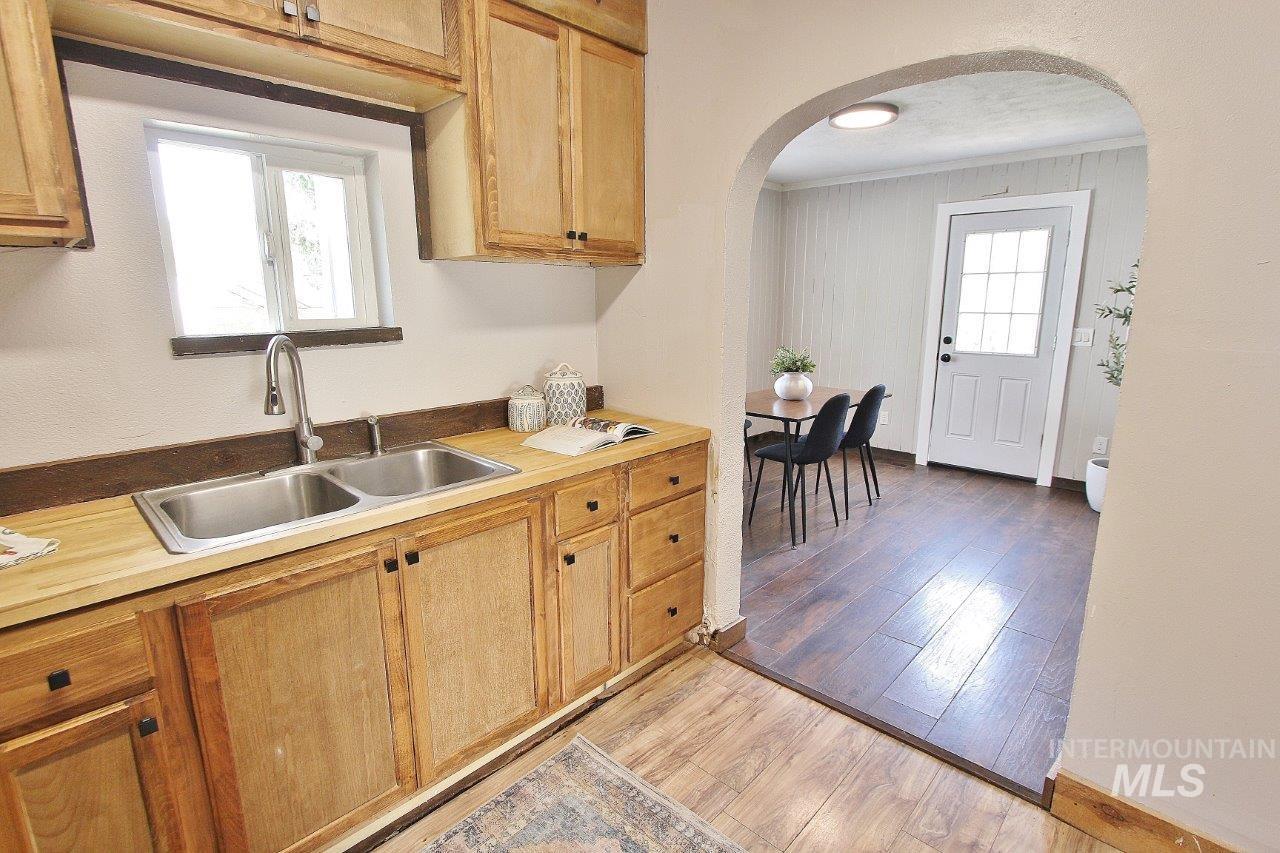 Kitchen with light wood-style floors, arched walkways, and ornamental molding