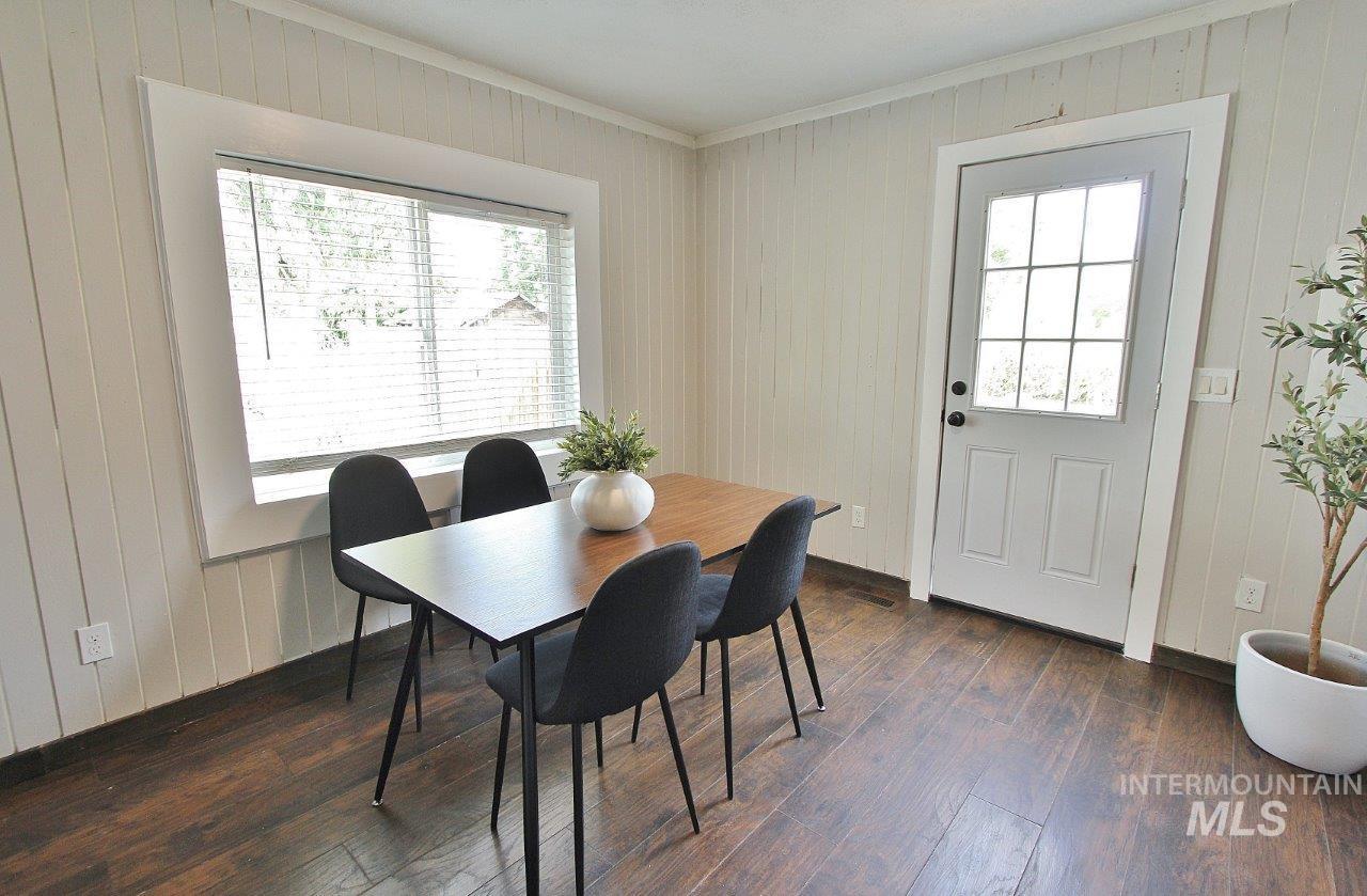 Dining space featuring wood walls, dark wood-style floors, and crown molding