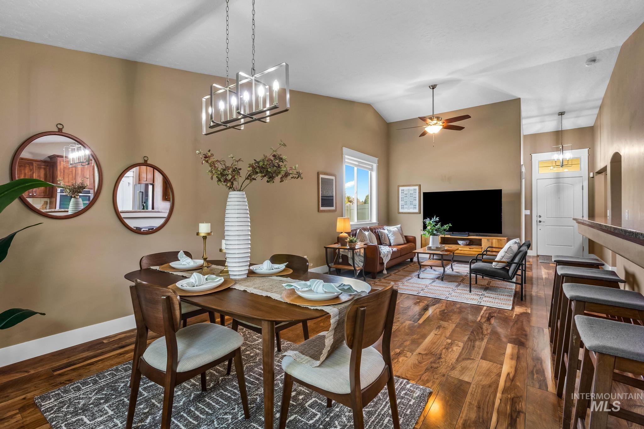 Dining room with a chandelier, dark wood finished floors, lofted ceiling, and a ceiling fan