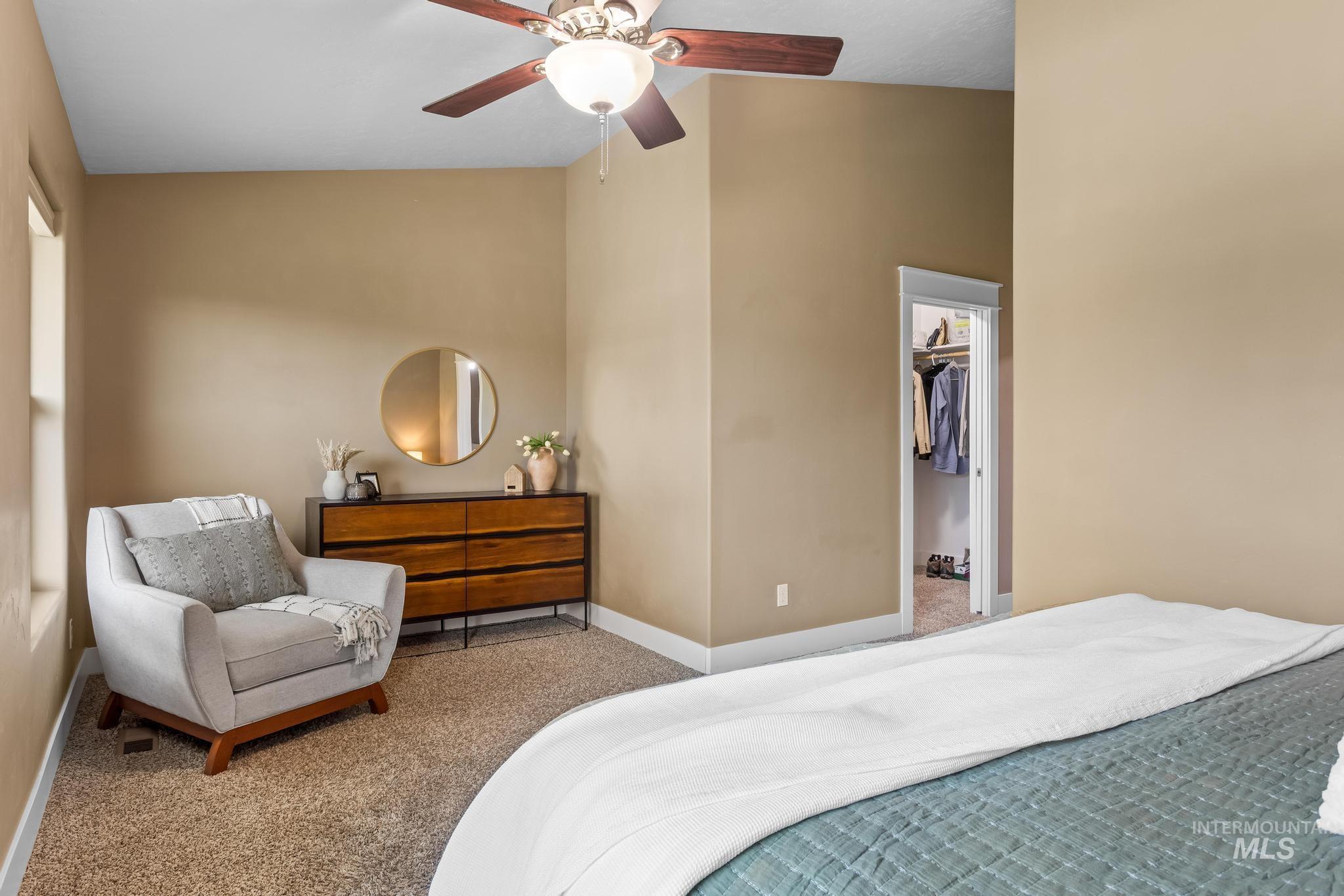 Carpeted bedroom with a walk in closet and ceiling fan