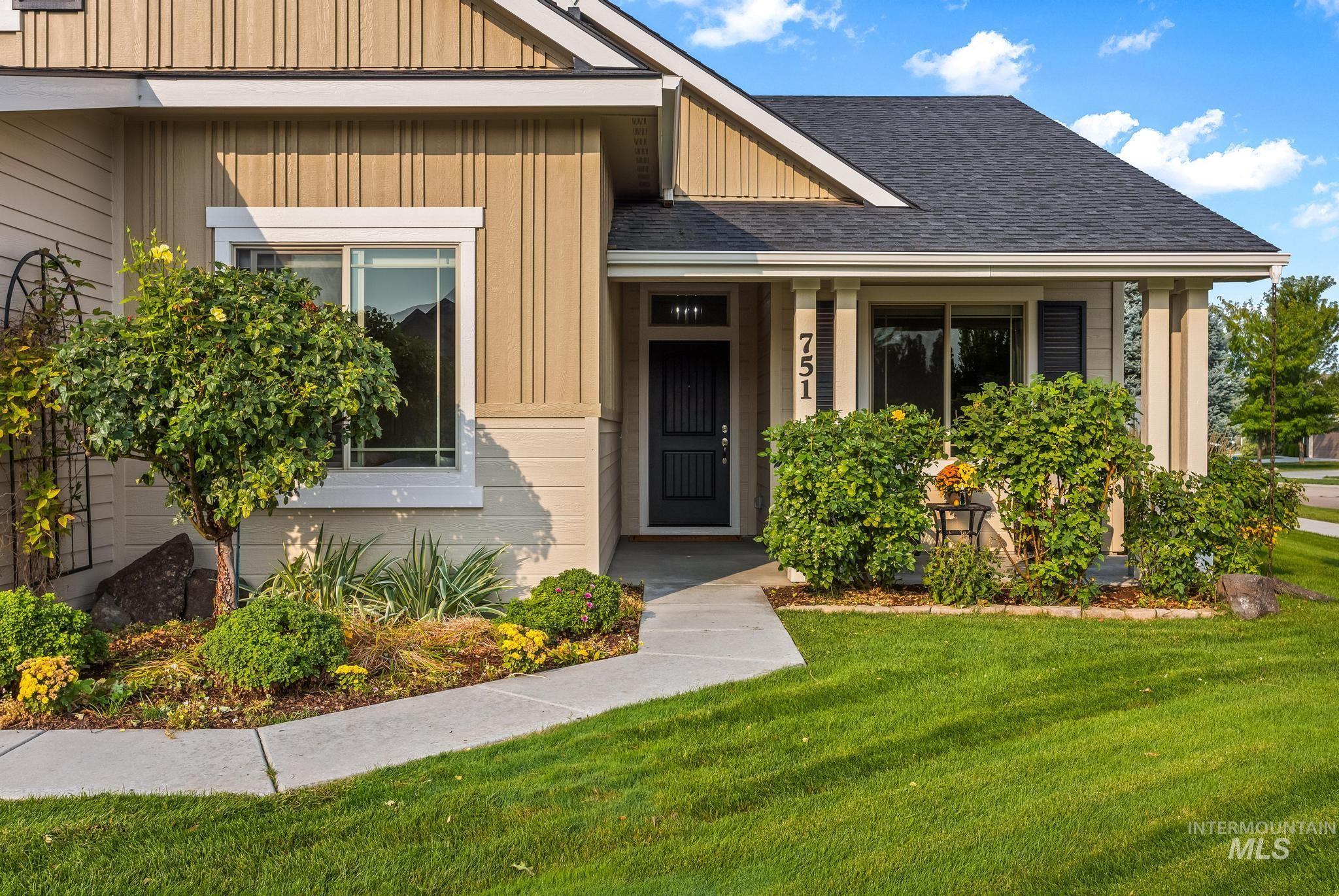 Property entrance with board and batten siding, a lawn, a shingled roof, and covered porch