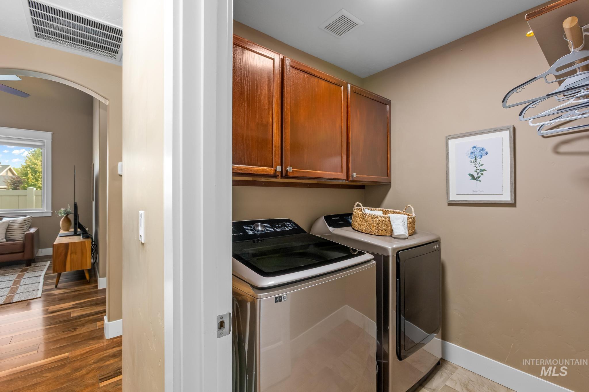 Washroom featuring arched walkways, cabinet space, washer and clothes dryer, and light wood-style floors